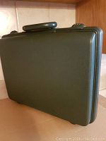Closed dark green hard-sided MACH2 attache case with combination locks and handle.