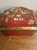 Top of the vintage tin box showing peacock birds, flowers, and calendar dials set to Sep 14.