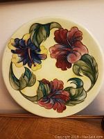 Full view of the vintage Moorcroft floral ceramic plate showing the round shape and colorful flower design.