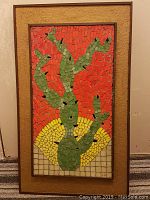 Framed cactus mosaic plaque showing the full design and frame, displayed upright against a wall.