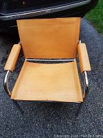 Front view of tan vinyl chair with chrome frame showing seat, backrest, and armrest pads.