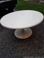Front side view showing smooth round white tabletop with minor blemishes on surface.