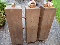 Three heavy wooden rectangular blocks connected with metal rods, photographed outdoors showing top detail and construction.