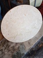 Top-down view of the round marble table top showing its light cream color with natural veining and polished surface.