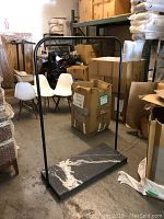 Full view of metal garment rack with black marble base in warehouse setting.