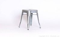 Single silver metal Tolix stool angled view showing seat and legs.