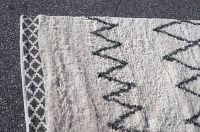 Close-up of edge corner showing border pattern and texture of the shaggy pile.