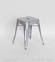 Single Tolix metal stool angled view showing metal legs, seat with handle cutout, and texture of galvanized finish.