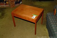 Full view of the wooden side table, showing its rectangular shape, four legs, and the wood grain finish on top.