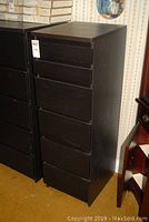 View of full side and front of tall dark wood IKEA Malm 6 drawer lingerie cabinet showing its narrow design and drawer fronts.
