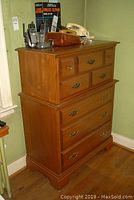 Overall front view of two-piece maple dresser with five drawers and brass-tone hardware