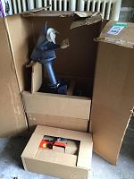 Outboard motor seated in original box showing grey housing and white three-blade propeller