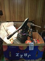 Industrial bow maker in a box with papers and some ribbon rolls visible