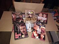 Box with DVD movies including 'The Swap', 'John Wayne' collection, 'Finding Neverland', 'An Innocent Man' and a multi-disc set with female leads on cover.