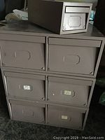 Front view of three larger metal stacking card holders in a 2x2 arrangement with one drawer missing on top and one smaller drawer placed on top