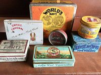 Seven assorted vintage tins arranged together, displaying variety in size, shape, and color with vintage branding.