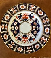 Top-down view of the decorated Royal Crown Derby plate showing full design with cobalt blue, red floral detail and gold accents.