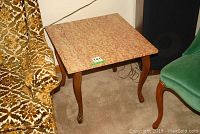 View of one end table showing marbled stone top and walnut finish curved legs.
