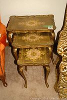 Full view of stacked set of three gold painted Venetian nesting tables showing ornate design and scalloped edges