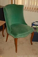 Front angled view showing green velour fabric upholstery and wood frame legs