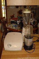 Wide view showing all three items on kitchen counter including the George Foreman grill, vintage blender, and Magic Bullet blender with accessories.
