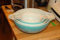 Side view of three nesting Pyrex bowls with Amish motif pattern in white on blue background, showing their size difference and handles