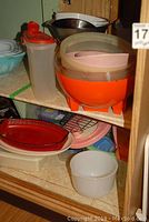 Photo showing assorted plastic storage containers, glass bowls, and pottery dishes on shelves.