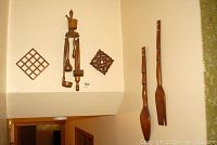 Wide view of corner with wood wall art kitchen utensils and trivets arranged. Includes lattice trivets and carved utensils hanging on wall.