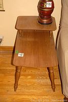 Front view of one vintage melamine telephone table with two tier design and turned wooden legs