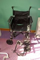 Front view of the black wheelchair showing seat, armrests, and front wheels.