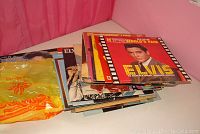Stack of Elvis Presley vinyl albums photographed on table showing multiple cover images.