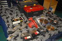 Overview of assorted power and hand tools laid out on patterned fabric including saws, toolboxes, leveler and blades