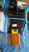 Photo showing overall lot on blue tarp, including miniature TV, LG Smart TV tuner box, Samsung VCR, binoculars in case, and yellow Sony Walkman
