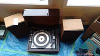 Turntable and two speakers photo showing overall lot contents with turntable in open wood casing and speakers on either side.