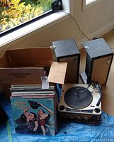 Photo showing the vintage Seabreeze turntable, two black speakers, and a cardboard box with vinyl records inside.