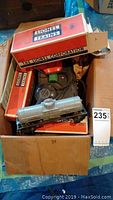 Box containing Lionel train cars, original boxes, and transformer.