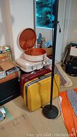 Vintage hard-sided luggage stacked - round cream suitcase open showing orange interior, burgundy suitcase in middle, yellow suitcase on bottom