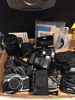 Overview of all items laid in box including cameras, lenses, flash and filter kits