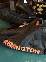 Remington black carrying/storage case with orange Remington branding placed on green surface.