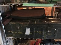 Photo of metal ammo box with visible yellow stenciled markings and signs of wear such as chips and scratches, taken to show the condition and type of container.