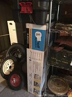 Photo showing the boxed shelving unit and a Rubbermaid Action Packer tote placed on and near metal shelving with assorted other items