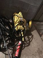 Photo of Karcher 570 pressure washer device with power cords, hose, brush attachment, and wand attachment on floor.