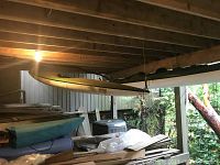 Kayak stored under wooden deck, showing surrounding area and storage environment.