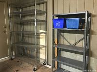 Full view of the two shelving units side by side, one on wheels and the other freestanding with solid shelves.