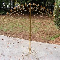 Full front image of very large metal candelabra standing outdoors showing size and structure.