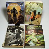 Four vintage hardcover science fiction books with dust jackets, showing spines and front covers, arranged on surface. The Kif Strike Back, Chanur's Homecoming, Arafel's Saga, and Leviathan's Deep visible.
