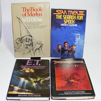 Overview of four hardcover science fiction and fantasy books with dust jackets: 'The Book of Merlyn,' 'Star Trek III The Search for Spock,' 'E.T. The Extra-Terrestrial,' and 'Dragonslayer'.