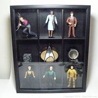 Shadow box housing six 5" Star Trek action figures with a Plexiglass cover, showing Captain Picard, Guinan, Captain Kirk, Worf, Kes, and Dixon Hill figure along with Borg cube model and TNG Personal Communicator