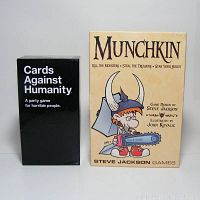 Both game boxes - Munchkin and Cards Against Humanity standing upright on a white surface.