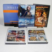Photo showing five DVD cases: House Season One set, Master and Commander The Far Side of the World unopened, Indiana Jones and The Kingdom of the Crystal Skull, and two TCM Greatest Classic Films Collections (Westerns and War), both unopened.